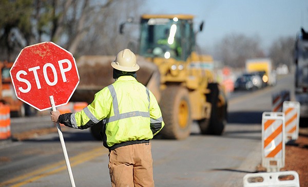 A worker with Sweeter Construction in Fayetteville holds a stop sign Thursday, Dec. 26, 2013, while directing traffic as a loader moves dirt as work continues along Garland Avenue near Noelle Avenue in Fayetteville.