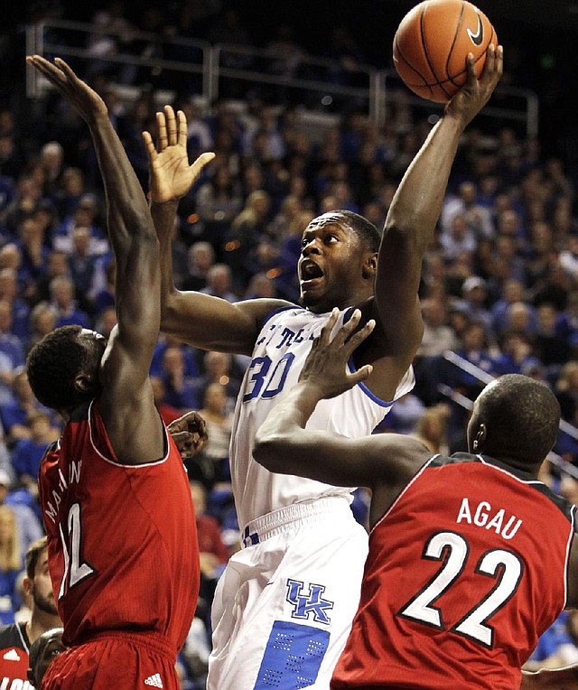 Kentucky’s Julius Randle (center) shoots between Louisville’s Mangok Mathiang (left) and Akoy Agau during the second half of Saturday’s game in Lexington, Ky. Randle scored 17 points in the first half and finished with 21 as Kentucky won 73-66. 