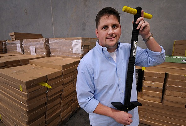 Rodney Redman, Executive Vice President and Chief Operating Officer of Redman & Associates, holds a Zumu pogo stick while standing amongst pallets of the toys waiting to be shipped at the new Redman & Associates facility in Rogers on Wednesday December 18, 2013.
