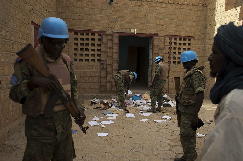 FILE - In this July 23, 2013 file photo, United Nations peacekeepers search a house suspected to have been used by members of al-Qaida’s North African branch in Timbuktu, Mali. The al-Qaida cell occupied Timbuktu for 10 months until January 2013. When they fled, they left behind thousands of pages of documents, including over 100 receipts, showing that they assiduously tracked their cash flow, down to the $0.60 one of them spent for a single light bulb. The accounting system on display suggests that far from being a fly-by-night terror organization, al-Qaida is attempting to behave like a corporation. (AP Photo/Rebecca Blackwell, File)