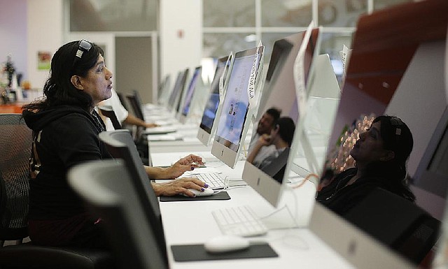 FILE - In this Dec. 11, 2013, file photo, Rosemary Cabelo uses a computer at a public library to access the Affordable Health Care Act website in San Antonio. The Obama administration says following a December surge, more than 1.1 million people have now enrolled for health insurance through the federal government’s improved website. (AP Photo/Eric Gay, File)