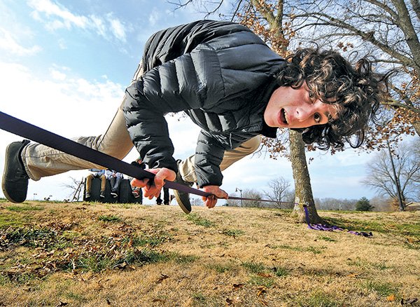 STAFF PHOTO BEN GOFF 
Zane Signorino, 18, balances on his hands Wednesday while trying out the new slack line kit he got for Christmas at Memorial Park in Bentonville.