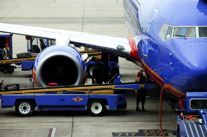 A Southwest Airlines Co. employee waits to unload baggage from a plane sitting on the tarmac at Minneapolis-St. Paul International Airport (MSP) in Minneapolis, Minnesota, U.S., on Sunday, Sept. 8, 2013. Yields on benchmark securities climbed to almost two-year highs as consumers spent more on travel and tourism while manufacturing expanded ìmodestlyî from early July through late August, according to the Federal Reserveís Beige Book. Photographer: Patrick T. Fallon/Bloomberg