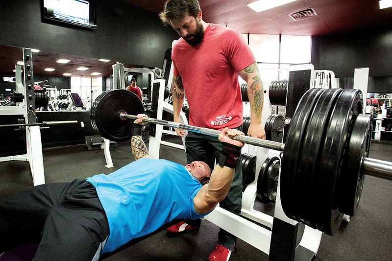 Phillip Brewer benchpresses at 365 Fitness in Conway while facility co-owner Anthony Sacomani spots for him.