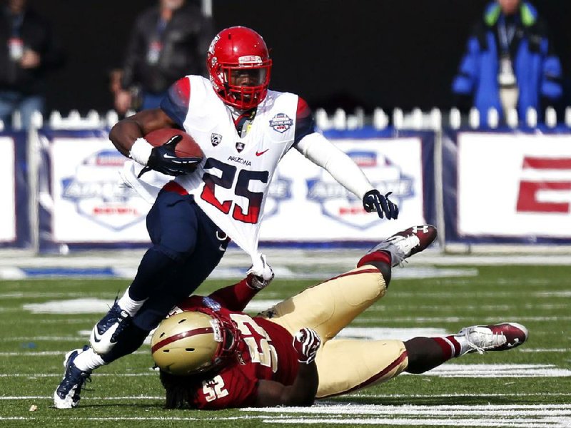 Arizona running back Ka’Deem Carey (25) is flung down by Boston College linebacker Steve Daniels in the second half of the Wildcats’ 42-19 victory in the AdvoCare Bowl on Tuesday in Shreveport. Carey rushed for 169 yards and 2 touchdowns, out dueling Boston College’s Andre Williams, a Heisman Trophy finalist. Williams finished with 75 yards rushing. 