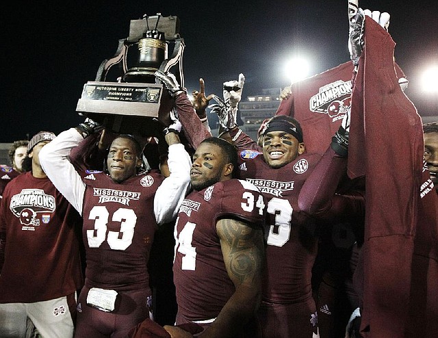 Mississippi State’s Kivon Coman (33), Josh Robinson (34) and Michael Hodges celebrate with the Liberty Bowl trophy after defeating Rice 44-7 on Tuesday in Memphis. It was the lopsided outcome in the game’s 55 years. 