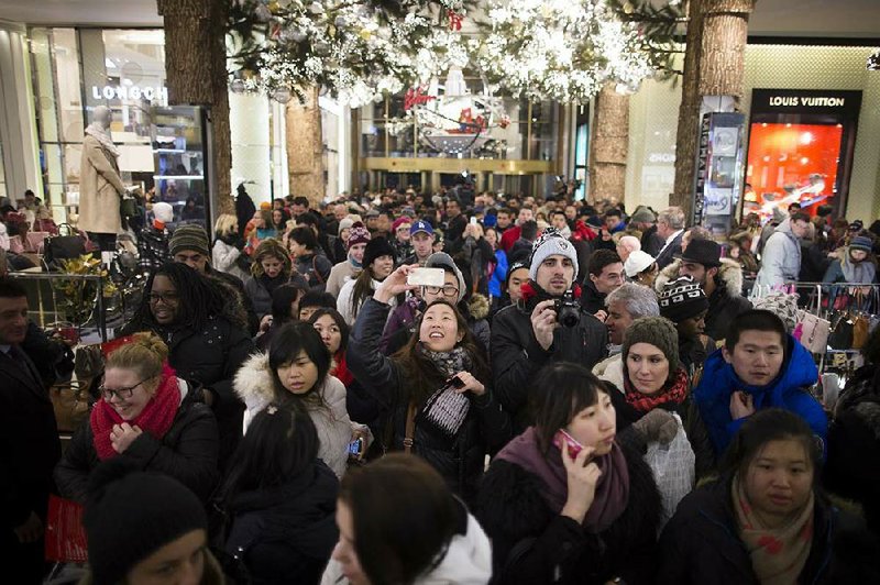 A shopper stops to take a selfie as crowds pour into the Macy’s Herald Square flagship store in New York on Nov. 28. A new report said consumer confidence rose in December as steady job gains and a surging stock market made Americans more optimistic about the economy and hiring. 