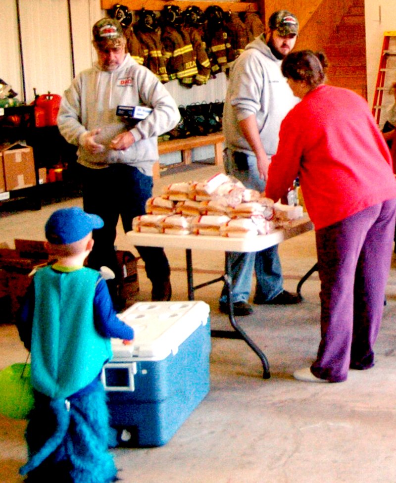 Photo by Mike Eckels Decatur Fire Chief David Flynt, top left, and Assistant Fire Chief Jeremy Luker hand out goodies during the Fire Department Halloween open house on Oct. 31. Flynt is stepping down Jan. 1. Luker will take over his duties. Flynt, a 23-year veteran of the department, will continue to work as a volunteer firefighter.