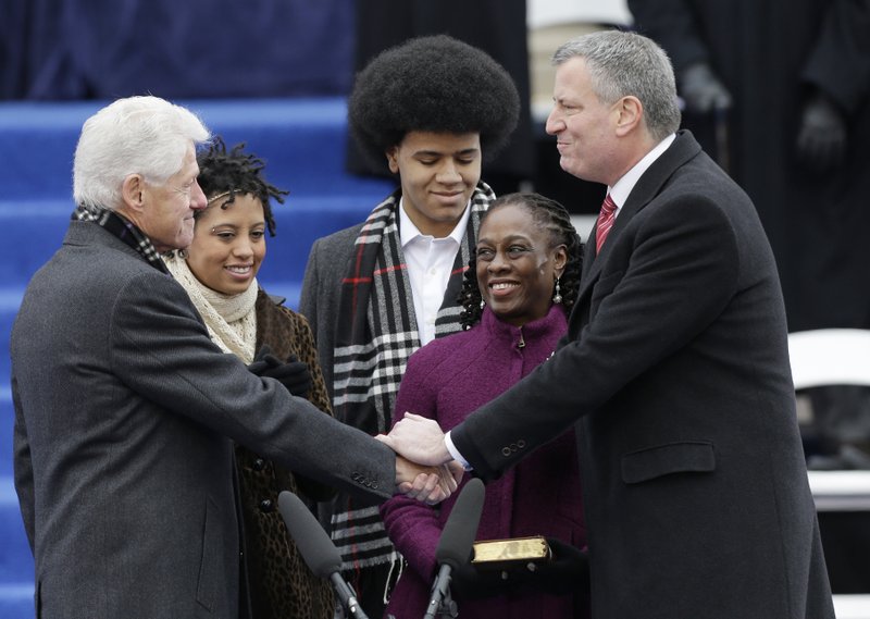 Former President Bill Clinton, administers the oath of office to Mayor-elect Bill de Blasio as his wife Chirlane McCray, second from right, Dante de Blasio, center, and Chirlane McCray watches on the steps of City Hall Wednesday in New York.