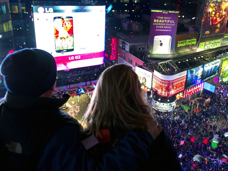Kenn Magowan, left, Anna Edgerly-Moore, both of New York, look out over Times Square, Wednesday, Jan. 1, 2014 as the new year is celebrated. 