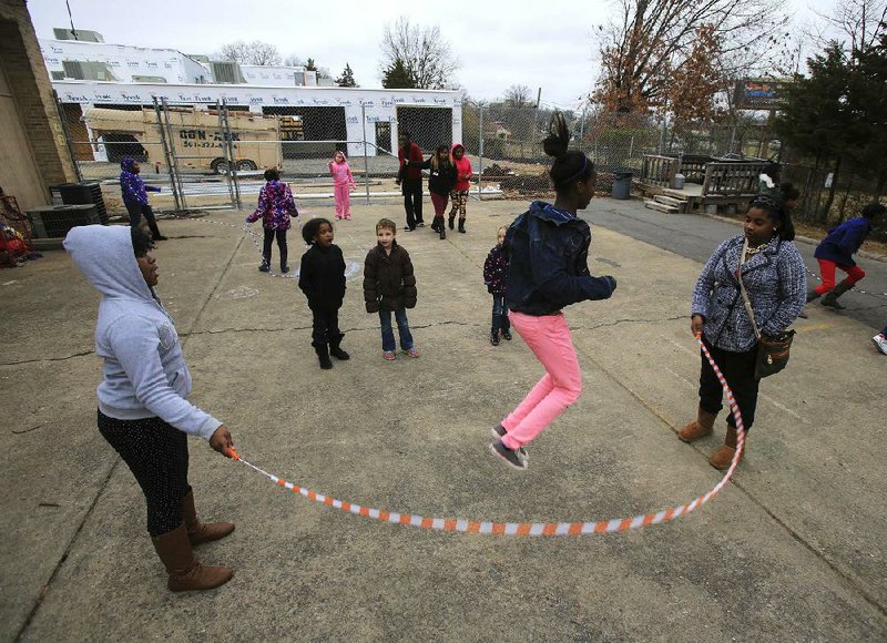 Aniyah McCather (left) and Tierra Bohanan spin a jump rope for Jazorah Gregory on Monday afternoon on the playground at Our House in Little Rock. The new children’s center, under construction in the background, will allow the organization to serve more than twice the number of children currently in its programs. 