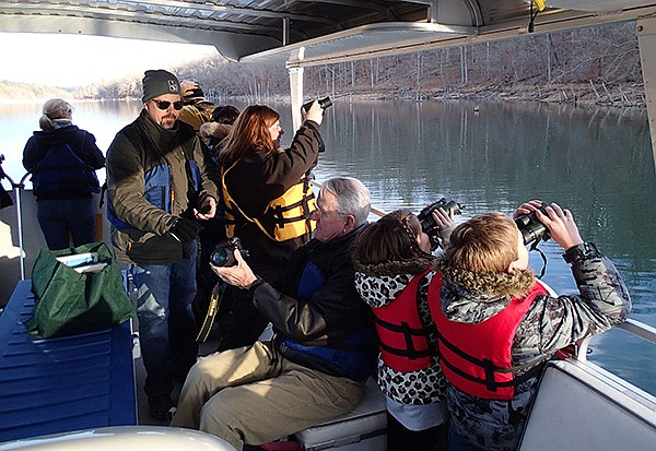 STAFF PHOTO FLIP PUTTHOFF 
Eagle tour passengers look Saturday at a bald eagle perched in a shoreline tree in the Van Winkle Hollow arm of Beaver Lake. Seven eagles, a loon and numerous ducks and geese were seen Saturday.