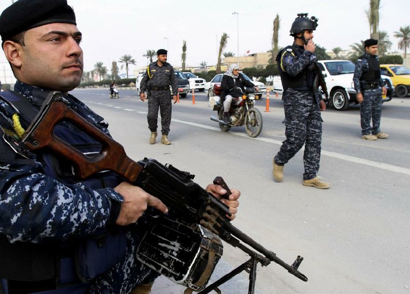 Iraqi federal policemen stand guard at a checkpoint in Basra, Iraq's second-largest city, 340 miles (550 kilometers) southeast of Baghdad, Iraq, Thursday, Jan. 2, 2014.  The Iraqi government has tightened its security measures after security forces have arrested, Wathiq al-Batat, a controversial Shiite cleric who leads an Iranian-backed militia called Mukhtar Army. (AP Photo/Nabil al-Jurani)