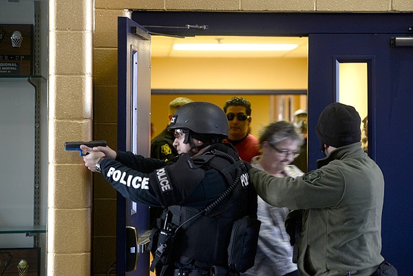 Springdale SWAT team members secure a door as civilians are evacuated from the area during an active shooter training scenario Thursday, Jan. 2, 2014 at Shiloh Christian School in Springdale. Several members of the police and fire departments and many people serving as students and teachers in the school helped in the training. Police used airsoft guns and others loaded with blanks.