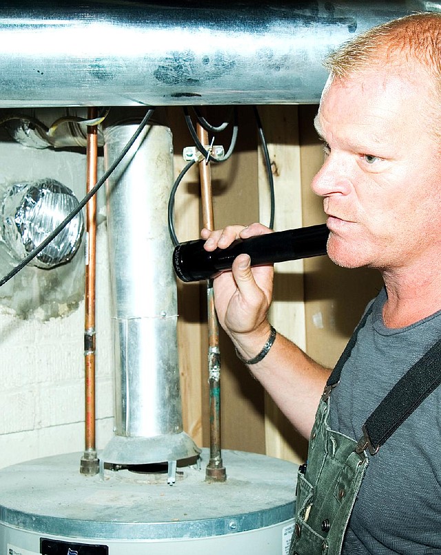 AT HOME for release DECEMBER 2013 DESIGN SCHOOL Caption 02: Author and contractor Mike Holmes notes problems with the exhaust venting from a gas water heater, a critical problem that would be caught during a thorough home inspection. 