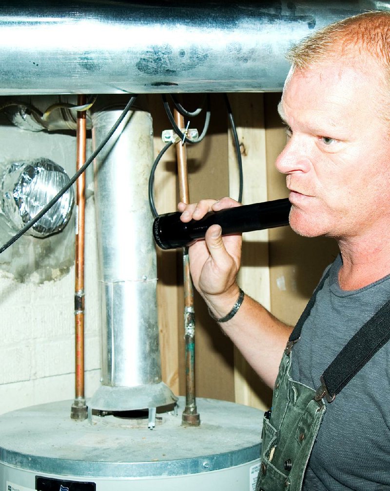 AT HOME for release DECEMBER 2013 DESIGN SCHOOL Caption 02: Author and contractor Mike Holmes notes problems with the exhaust venting from a gas water heater, a critical problem that would be caught during a thorough home inspection. 