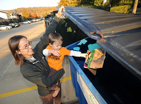 Stephanie Kellner, left, holds her 2-year-old son, August, so he can deposit paper into a recycling container Tuesday, Nov. 1, 2011, at The Cliffs, an apartment complex in east Fayetteville. The City of Fayetteville is launching a program that will allow citizens who live in apartments to recycle using containers that are currently being rotated between five area complexes. "I saw this yesterday and I was so happy," said Kellner.