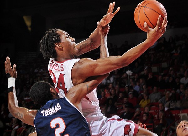 Arkansas forward Michael Qualls is fouled by Hyjii Thomas as he drives to the basket in the first half at Bud Walton Arena in Fayetteville on Saturday Jan. 4, 2013. 