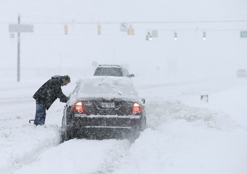 A motorist helps dig out a driver stuck in a snow drift Sunday, Jan. 5, 2014, in Zionsville, Ind. Snow that began in parts of Indiana Saturday night picked up intensity after dawn Sunday with several inches of snow on the ground by midmorning and more on the way.(AP Photo/Darron Cummings)