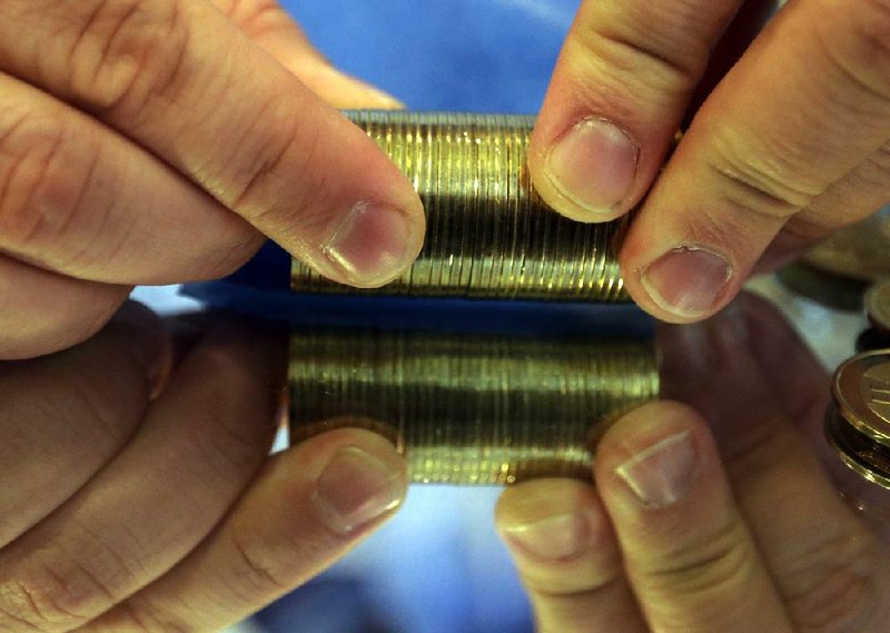 FILE - In this April 3, 2013 file photo, Mike Caldwell, 35, rolls a stack of bitcoin tokens at his shop in Sandy, Utah. Just as miners dig up precious metals, Bitcoins are mined digitally. Developed at the start of 2009 by an anonymous computer programmer, Bitcoins have been associated with the drug trade and tax avoidance. Because there is a finite supply of just 21 million Bitcoins, the expectation among its devotees is that the currency will continue to appreciate. (AP Photo/Rick Bowmer)