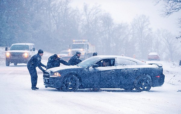 STAFF PHOTO ANDY SHUPE 
Fayetteville Police Sgt. Shannon Gabbard, left, Sgt. Tim Franklin, Cpl. David Williams and Cpl. Julia McKinney help a stranded motorist Sunday on Crossover Road as snow falls in Fayetteville.