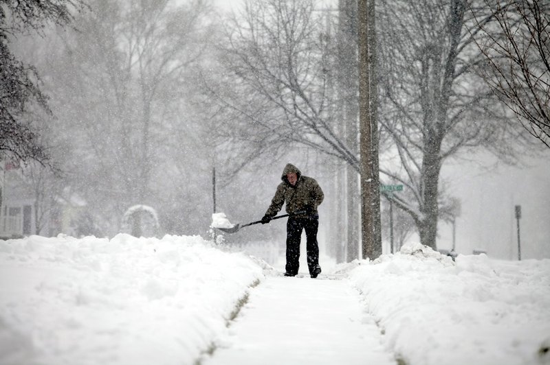 Snow builds as John McAvoy shovels his sidewalk Sunday, Jan. 5, 2014, in Bowling Green, Ohio. 