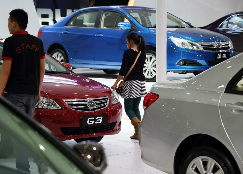 Visitors walk past BYD Co. vehicles displayed at the company's booth at the Wuhan Motor Show 2013 in Wuhan, China, on Saturday, Oct. 19, 2013. The show will be held through Oct. 23. Photographer: Tomohiro Ohsumi/Bloomberg