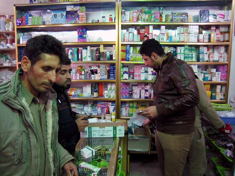 Civilians buy medicine from the only open pharmacy in Fallujah, 40 miles (65 kilometers) west of Baghdad, Iraq, Monday, Jan. 6, 2014. Clashes continued late Sunday and early morning Monday between al-Qaida and Iraqi troops on the main highway that links the capital, Baghdad, to neighboring Syria and Jordan. Al-Qaida fighters and allied tribes are still controlling the center of the city where they are deployed in streets and around government buildings. (AP Photo)