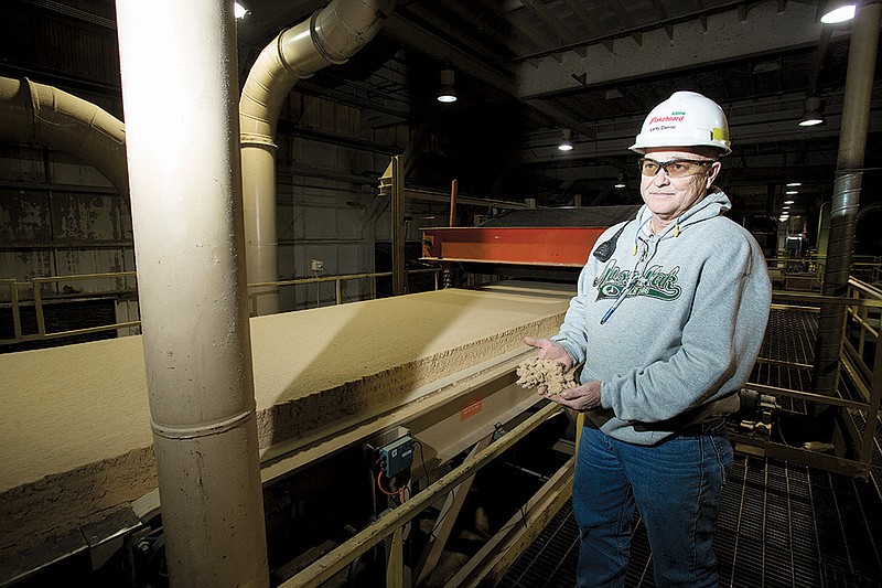 Larry Daniel, production supervisor for the Flakeboard America plant in Malvern, demonstrates that before pressure and curing, the mixture of ingredients for the company’s finished product is still sawdustlike.
