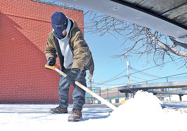 STAFF PHOTOS SAMANTHA BAKER 
• @NWASAMANTHA 
Brandon Sabart with Lawnworks shovels snow Monday off the sidewalk of the First Baptist Church’s Studio 412 Student Ministry in Bentonville. Sabart said his shovel broke trying to pry up ice that has coated the sidewalks and parking lots in the area.