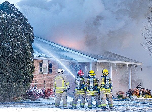 STAFF PHOTOS ANTHONY REYES 
Springdale firefighters direct water to the roof of a house Monday at 2206 Monticello Place in Springdale. After the fire spread into the attic, firefighters were forced to evacuate the house and fight the fire from the exterior.