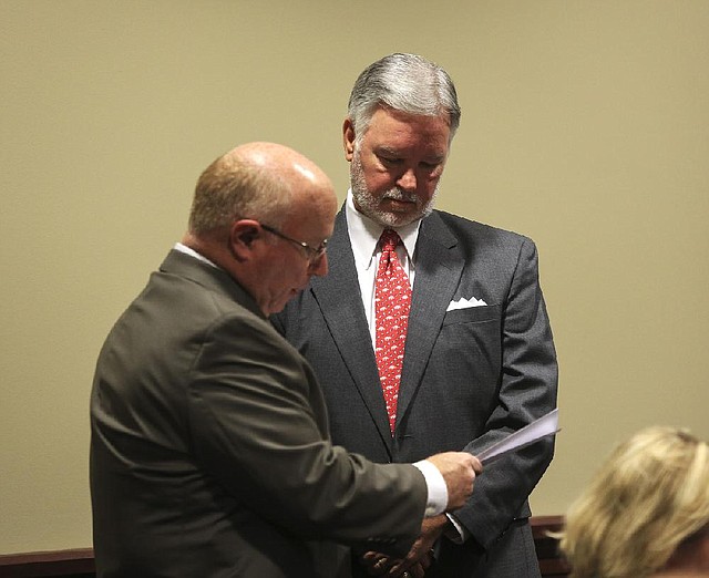 Capt. Lindsey Williams of the Arkansas State Police (left) serves a legislative subpoena Tuesday to Brad Choate, former University of Arkansas at Fayetteville vice chancellor of advancement, requiring Choate to testify before the Legislature’s Joint Performance Review Committee. 