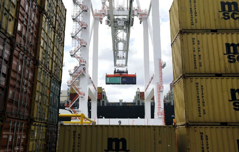 A crane unloads a freight container last spring at the Port of Baltimore. A pickup in manufacturing is helping narrow the U.S. trade deficit, officials said Tuesday. 