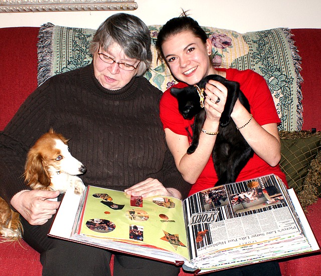 Photo by Dodie Evans Exchange student Sarah Peronne cuddles Izzy and host mother Karen Kerr holds Reese while they enjoy looking through the thick scrapbook of first semester memories.