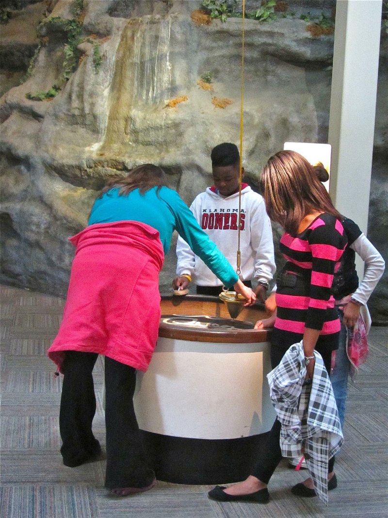 Visitors to Hot Springs’ Mid-America Science Museum experiment with the facility’s Sand Pendulum. 