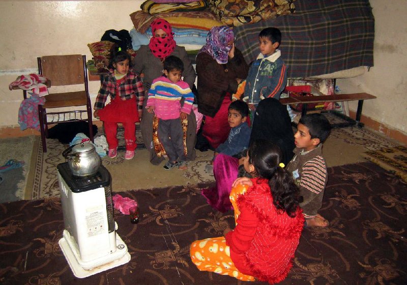 Sunnis who fled the Iraqi city of Fallujah warm up around a heater Wednesday in a school in Baghdad. 