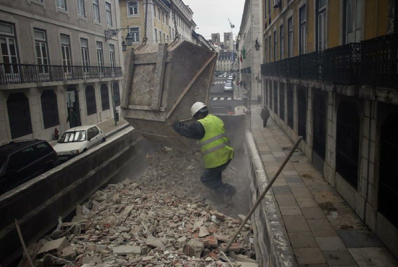 A construction worker fills a truck with debris next to the Bank of Portugal headquarters in Lisbon on Wednesday. Glimmers of hope emerged Wednesday from the eurozone economy to suggest that the coming year will see the recovery picking up steam. 