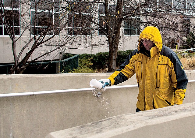 Roger Harris spreads salt Wednesday outside a business off Sixth Street in downtown Little Rock. 