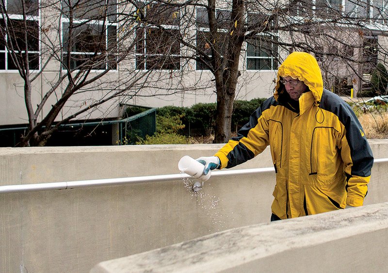 Roger Harris spreads salt Wednesday outside a business off Sixth Street in downtown Little Rock. 