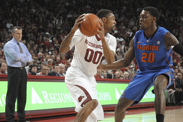 Arkansas guard Rashad Madden (00) looks for room while being guarded by Florida guard Michael Frazier II (20) as Florida coach Billy Donovan, left, watches in Fayetteville, Ark. during an NCAA college basketball game Saturday, Jan. 11, 2014. Florida won 84-82 in overtime. (AP Photo/David Quinn)