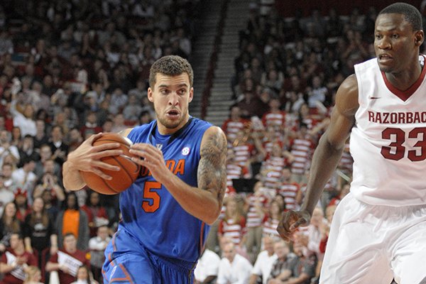 Florida guard Scottie Wilbekin (5) drives past Arkansas center Moses Kingsley (33) during an NCAA college basketball game at Walton Arena in Fayetteville, Ark., Saturday, Jan. 11, 2014. Florida defeated Arkansas 84-82 in overtime. (AP Photo/David Quinn)