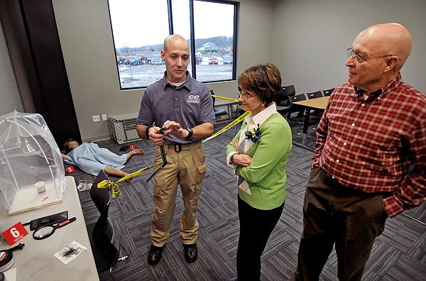 Adjunct instructor of Criminal Justice Brandon Dill, from left, a full-time officer with the Rogers Police Dept., shows fingerprinting technology to his parents Dianne Dill and J.B. Dill, who are financial supporters of Crowder College, during a ribbon-cutting and open house for Crowder College's new James B. Tatum Hall in Jane, MO, on Friday January 10, 2014.