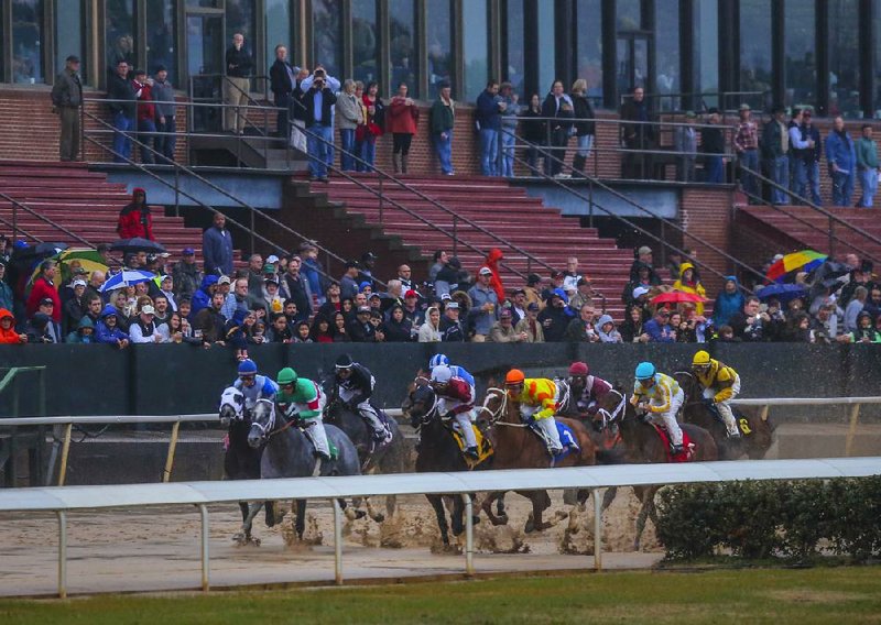 Racing fans gather near the front of the grandstand to watch the fifth race on opening day at Oaklawn Park in Hot Springs. An announced crowd of 15,031, the smallest opening-day crowd since 2003, braved chilly temperatures and plenty of rainfall. 