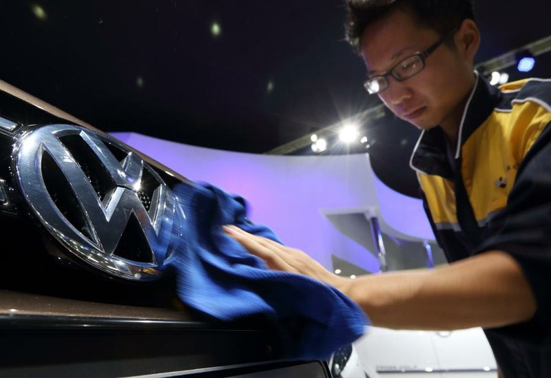 A worker wipes the Volkswagen logo on a vehicle displayed at the FAW Volkswagen booth, the joint venture between Volkswagen AG, and FAW Group Corp., at the Wuhan Motor Show 2013 in Wuhan, China, on Saturday, Oct. 19, 2013. The show will be held through Oct. 23. Photographer: Tomohiro Ohsumi/Bloomberg