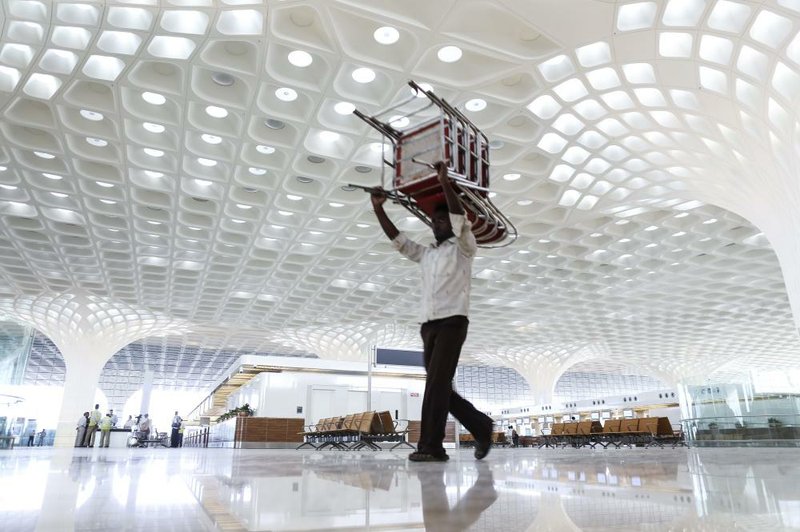 A worker carries a stack of chairs through the newly built Terminal 2 of the Chhatrapati Shivaji International Airport, operated by GVK Power & Infrastructure Ltd., in Mumbai, India, on Wednesday, Jan. 8, 2014. Mumbai airport will open a new international terminal, designed by Skidmore, Owings & Merrill LLP, in its first major upgrade in three decades as the nation aims to ease infrastructure constraints that hurt growth. Photographer: Dhiraj Singh/Bloomberg
