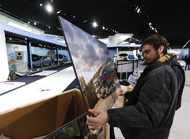 Worker Aaron Perry sorts the artwork for the General Motors Co. stand ahead of the 2014 North American International Auto Show (NAIAS) in Detroit, Michigan, U.S., on Thursday, Jan. 9, 2014. The show, which featured 71 vehicle debuts and attracted 795, 416 visitors in 2013, begins with a media preview on Jan. 13 and opens to the public on Jan. 18. Photographer: Jeff Kowalsky/Bloomberg *** Local Caption *** Aaron Perry