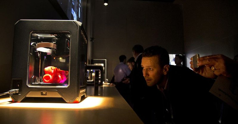 Trade show attendees examine the MakerBot Replicator Mini 3D printer at the International Consumer Electronics Show, Wednesday, Jan. 8, 2014, in Las Vegas. (AP Photo/Julie Jacobson)