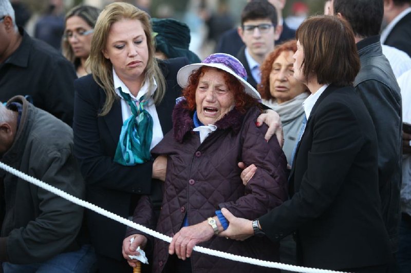 An Israeli woman mourns as she looks at the coffin of late Israeli Prime Minister Ariel Sharon at the Knesset plaza, in Jerusalem, Sunday, Jan. 12, 2014. Sharon, the hard-charging Israeli general and prime minister who was admired and hated for his battlefield exploits and ambitions to reshape the Middle East, died Saturday, eight years after a stroke left him in a coma from which he never awoke. He was 85. (AP Photo/Sebastian Scheiner)