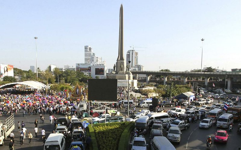 Traffic is at a stand still, right, at the Victory Monument as anti-government protesters, left, block the street Monday, Jan. 13, 2014, in Bangkok, Thailand. Thailand braced for a new wave of mass unrest Monday as anti-government demonstrators blocked major roads to "shut down" Bangkok in a bid to thwart February elections and overthrow the nation's democratically elected prime minister. (AP Photo/Apichart Weerawong)