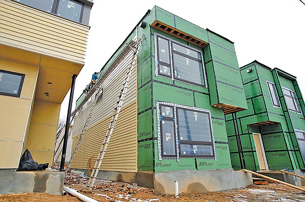 Siding is placed on single-family houses and duplexes 
Thursday at the intersection of West Avenue and Prairie Street in Fayetteville. The new construction by Jacobs & Newell Co. has a variety of “green” features, such as efficient insulation, low-flow faucets, recycled material or solar panels.